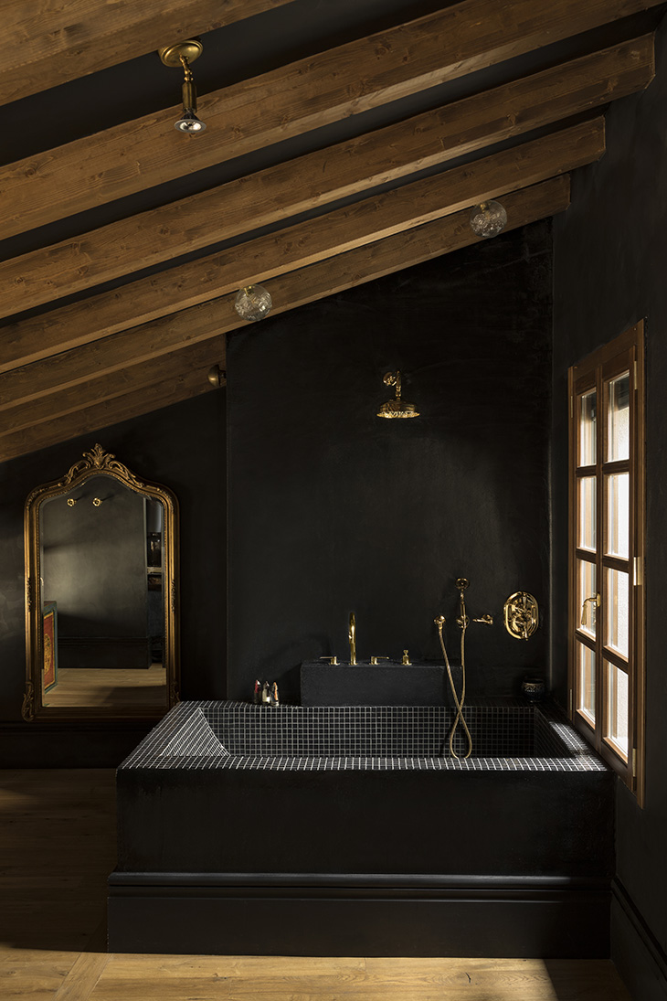 Diseño de hotel por Pablo Peyra Studio. Baño abuhardillado con bañera negra y grifería dorada bajo techo de madera. Diseño de hotel por Pablo Peyra Studio. Baño abuhardillado con bañera negra y grifería dorada bajo techo de madera.