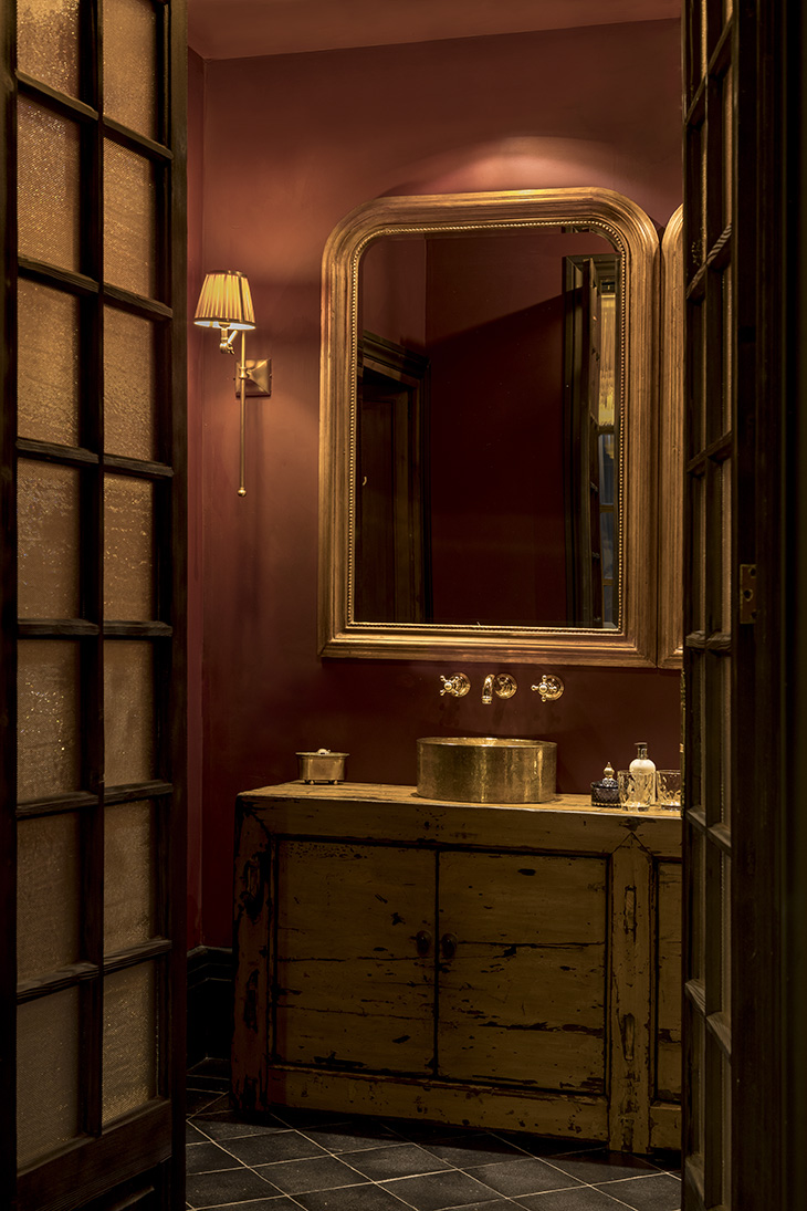 Mueble antiguo de madera con lavabo dorado y espejo clásico en aseo del Hotel Palma Riad, interiorismo de Pablo Peyra Studio. Mueble antiguo de madera con lavabo dorado y espejo clásico en aseo del Hotel Palma Riad, interiorismo de Pablo Peyra Studio.
