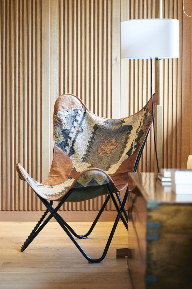 Diseño de interiores de residencial Les tres Torres, un proyecto de Pablo Peyra Studio. Vista detalle rincón silla diseño.