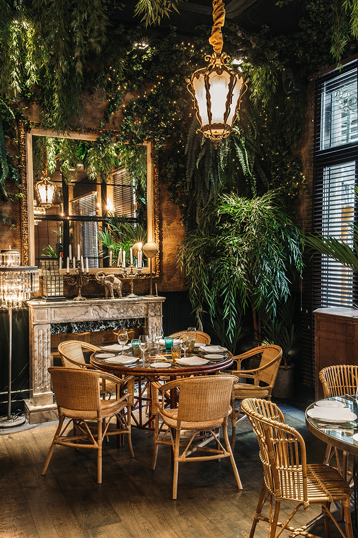 Diseño de restaurante por Pablo Peyra Studio. Proyecto Feroz. Vista detalle de comedor ambiente jungla con espejo, vegetación y muebles de bambú..