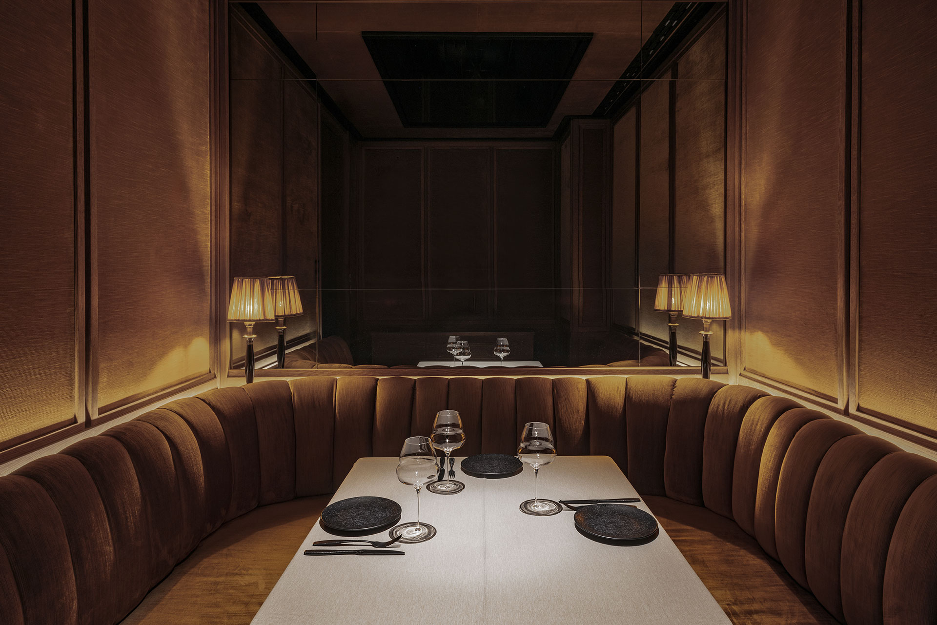 Restaurante Noble by Pablo Peyra Studio. Primer plano de mesa con sofá de banco corrido tapizado y pared de espejo. Restaurante Noble by Pablo Peyra Studio. Primer plano de mesa con sofá de banco corrido tapizado y pared de espejo.
